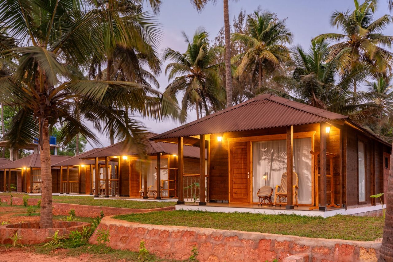 Wooden cottage lit up in the evening at Miraya by the Beach