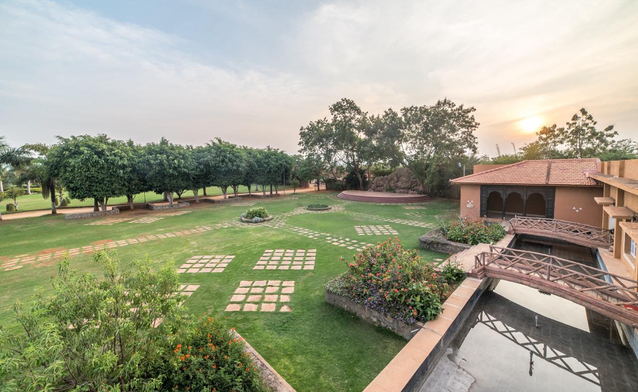Open lawn with seating and palm trees at Vijayshree Resort, Hampi